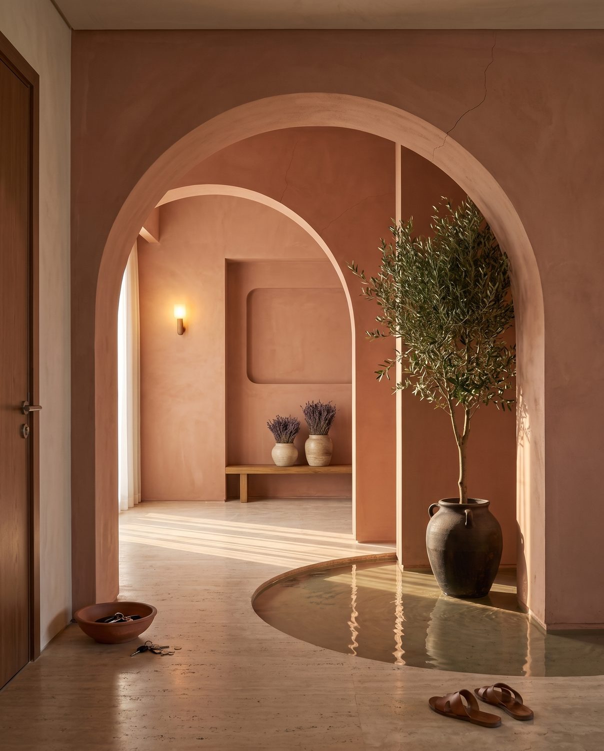 The entry: terracotta arches, a bowl for keys, an olive tree by the door