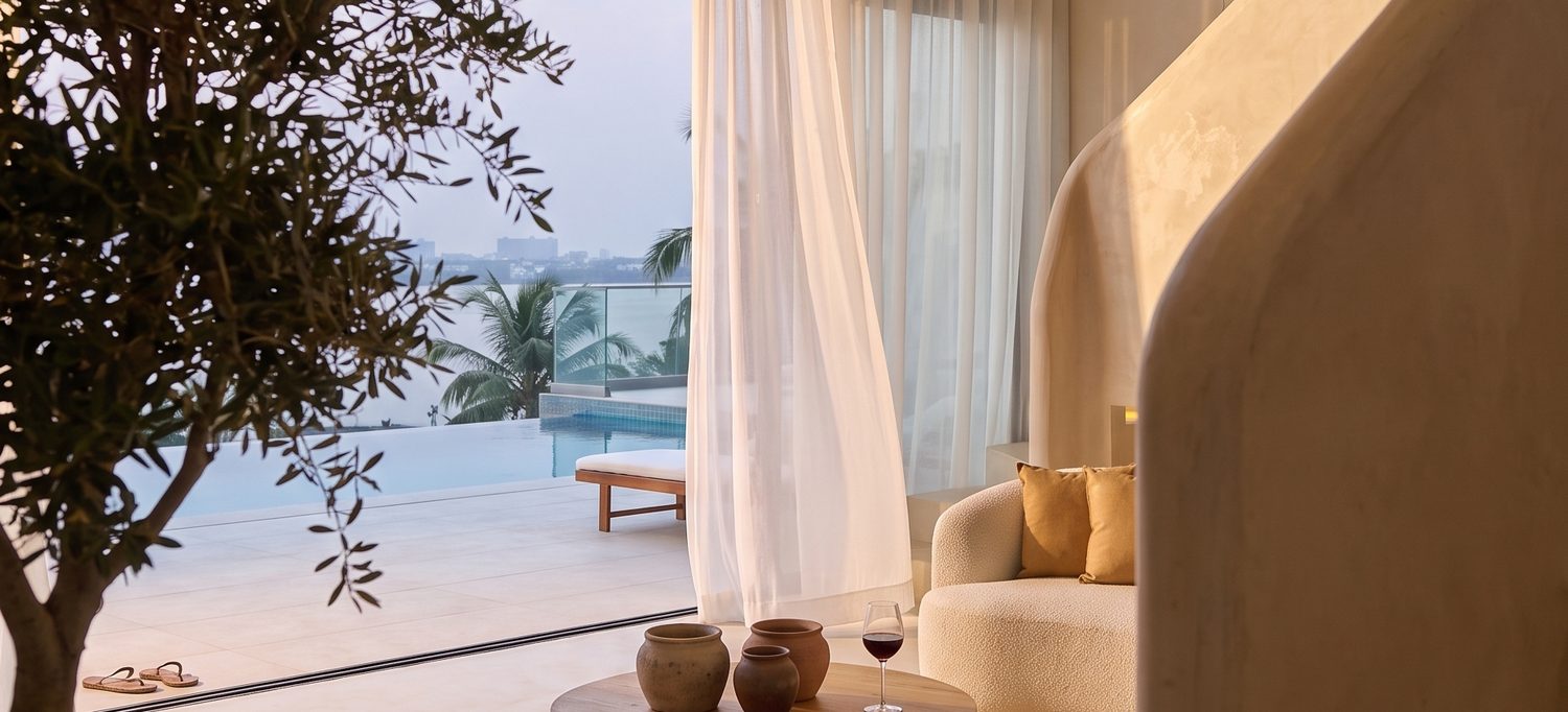 The living room at dusk, olive tree and sheers open to the pool